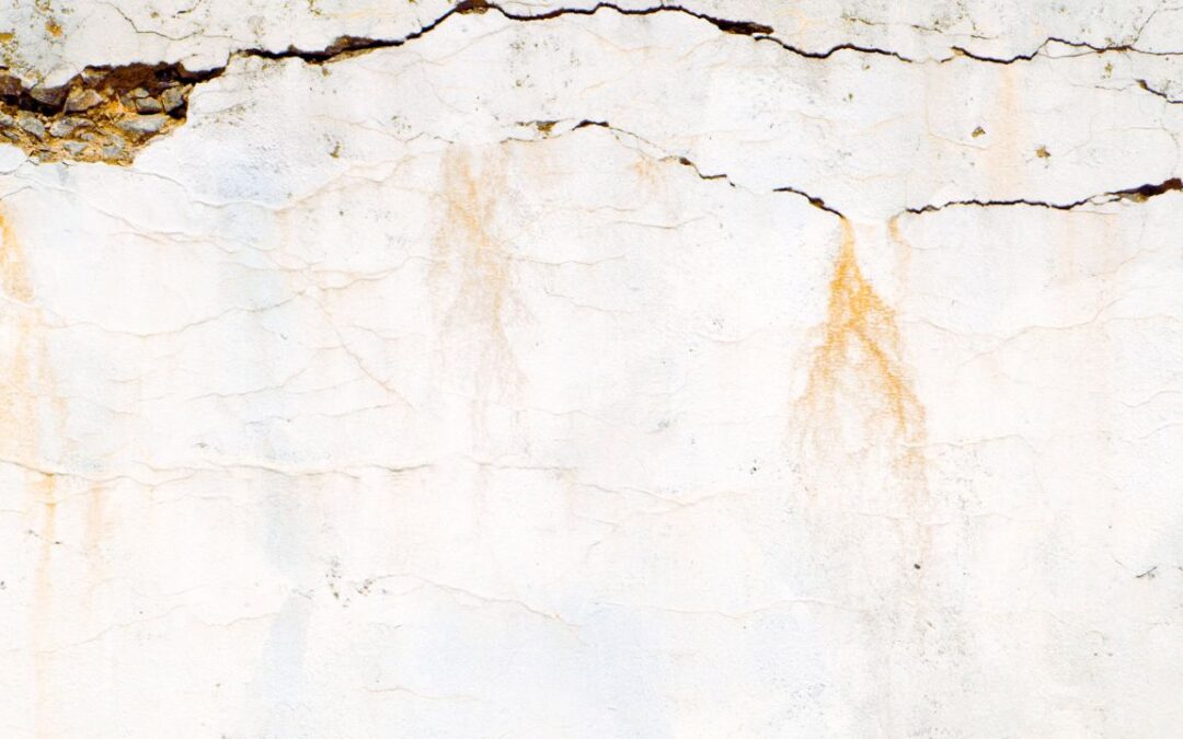 Retaining wall with visible cracks on sloped Missouri yard caused by soil pressure