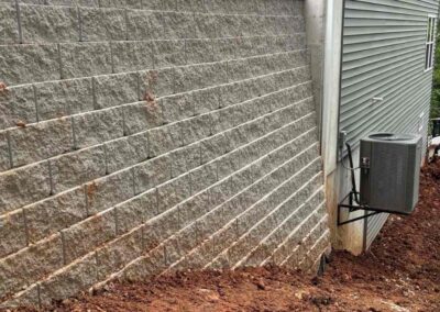 Close up of retaining wall foundation against St. Louis clay soil near home HVAC unit, built by Retaining Wall & Paving Solutions during dry season for stability