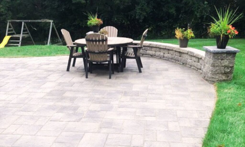 Concrete paver patio with round table, chairs, and curved retaining wall in a landscaped St. Louis backyard—example of durable hardscaping