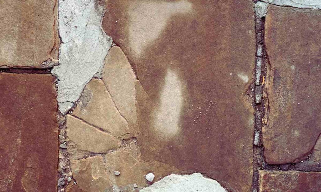 weather-worn stone pavers in St. Louis showing cracks, shifting, and patch repairs—highlighting common winter damage issues addressed during paver winterization.