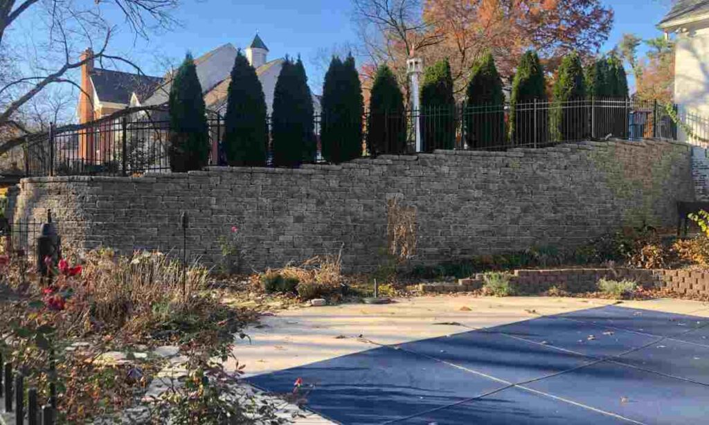 tall retaining wall supporting fence and elevated soil with surcharge load above