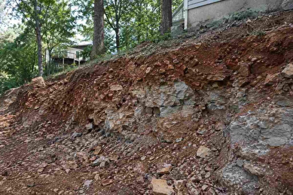Excavated Jefferson County hillside showing reddish chert-rich soil packed with rock fragments over shallow dolomite bedrock outcrop.